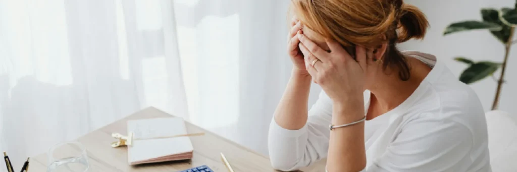 Mujer preocupada con las manos en la cara; reclamación de deudas y recobros.